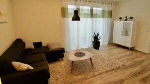Una sala de estar moderna con un sofá oscuro, una mesa de centro redonda y un armario blanco.