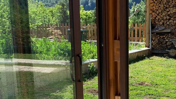 A table set for breakfast with a view of a garden and a wooden fence.