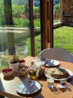A table set for breakfast with a view of a garden and a wooden fence.