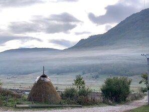 A rural landscape with a haystack and a mountain in the background.