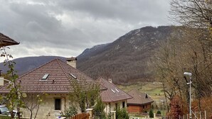 A residential area with houses having red-tiled roofs, a stone wall, and a gravel path.