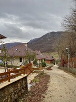 A residential area with houses having red-tiled roofs, a stone wall, and a gravel path.