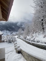 A snow-covered pathway leading to a building with a stone wall and a wooden roof.