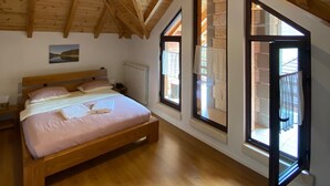 A bedroom with a wooden ceiling, a bed, and large windows.