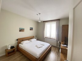Un dormitorio con una cama de madera, una mesita de noche con lámpara, una silla y un escritorio.