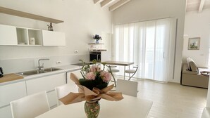 A modern kitchen with white cabinets, a wooden ceiling, and a dining area with a white table and chairs.