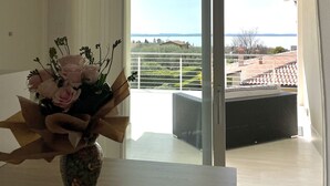 A room with a view of a balcony, a vase with flowers, and a window.