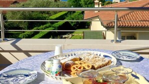 A balcony with a table set for breakfast, overlooking a coastal view.