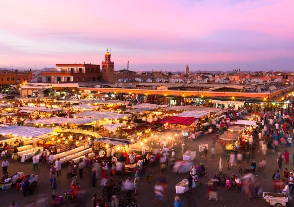 A bustling outdoor market with numerous stalls and people.