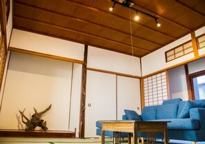 A traditional Japanese room with tatami flooring, a blue sofa, a wooden table, and a shoji screen.