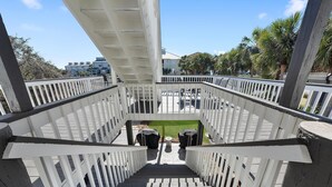 Una scala in legno conduce a una zona esterna coperta con vista su un edificio e palme.