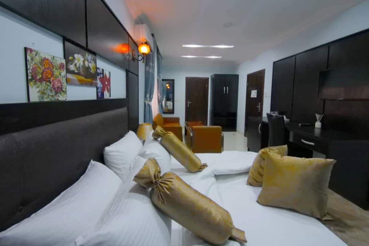 A hotel room with a bed, a desk, a television, and artwork on the wall.