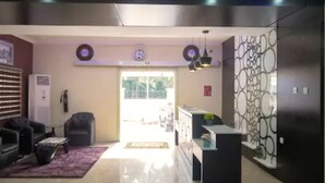 Un salon moderne avec un canapé, une table basse et un tapis à motifs. Il y a également un coin cuisine équipé d’un réfrigérateur et d’un évier.