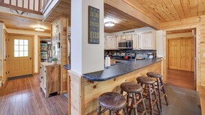 A spacious kitchen with wooden cabinets, a bar area with stools, and a sign that reads "Skiing spoken here."