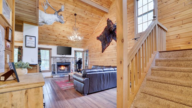 A wooden interior with a fireplace, leather sofa, and a mounted animal hide.