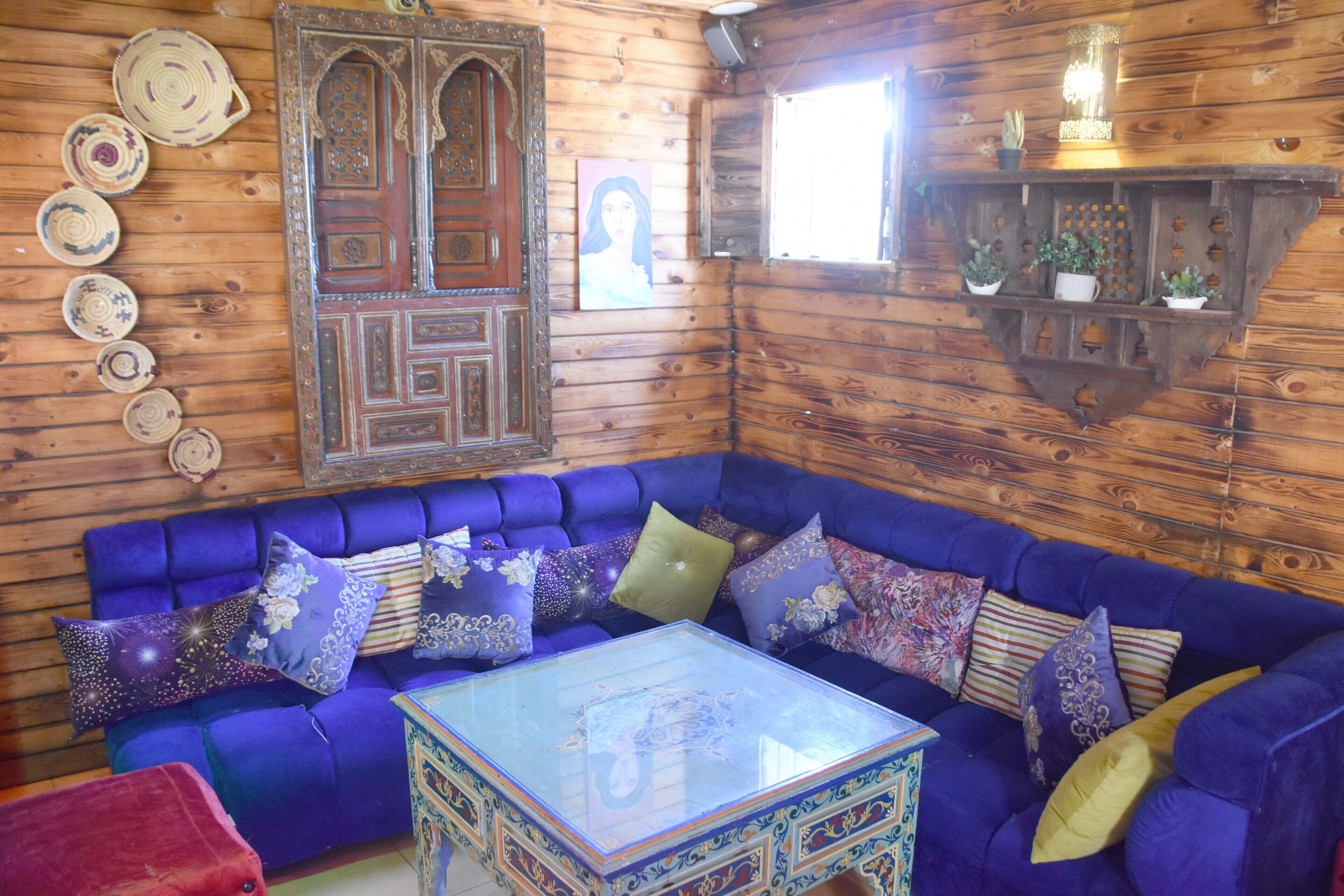 Um quarto aconchegante com um sofá azul, uma mesa de centro de vidro e paredes de madeira.