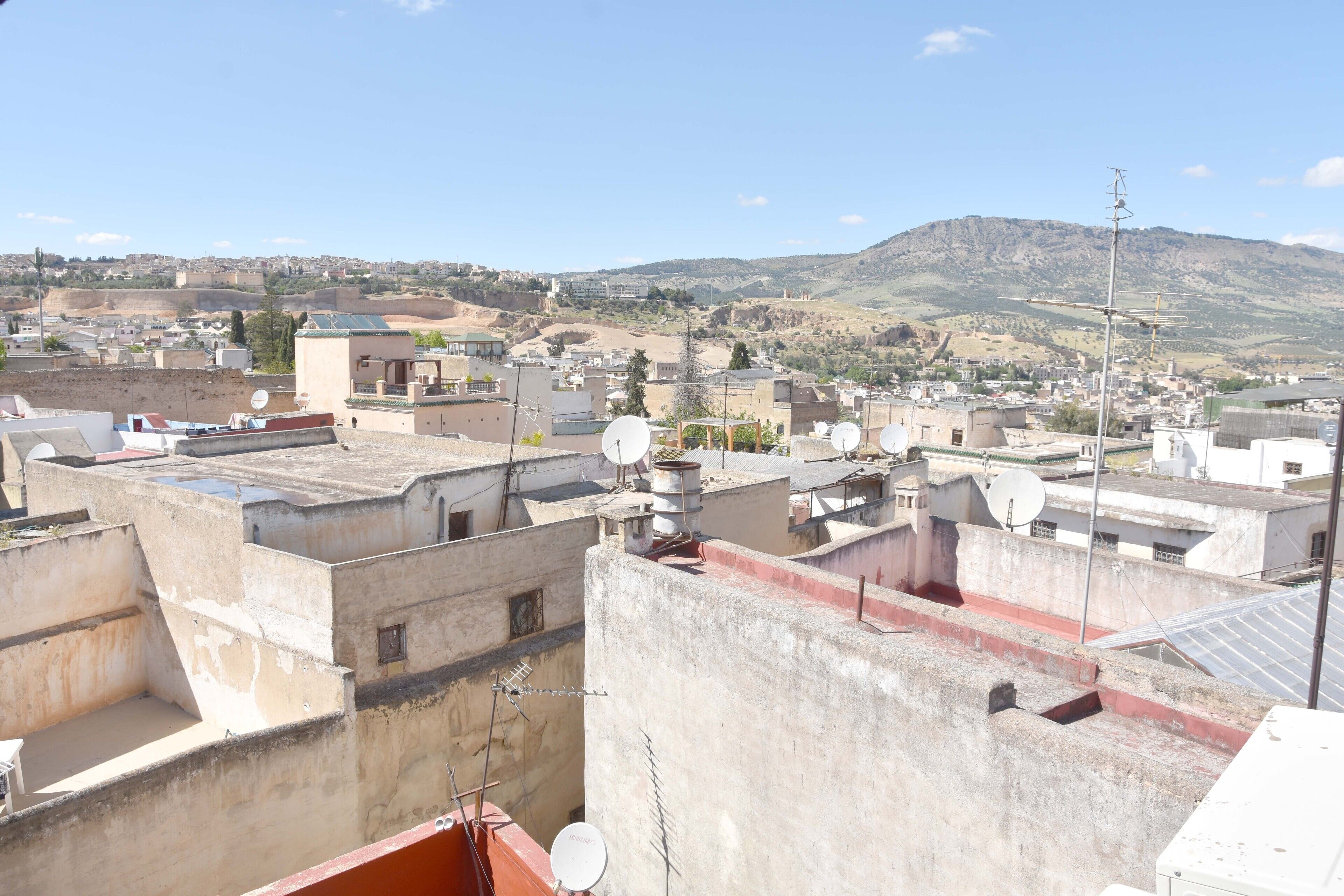 A cityscape with multiple buildings, satellite dishes, and a mountainous background.