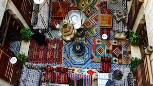 Um átrio multi nível com padrões complexos em azulejos, lanternas penduradas e diversos tecidos suspensos.