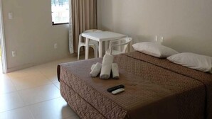 A hotel room with a bed, a desk, a chair, and a window with curtains. - Lebanon Praia Hotel (Tramandai)