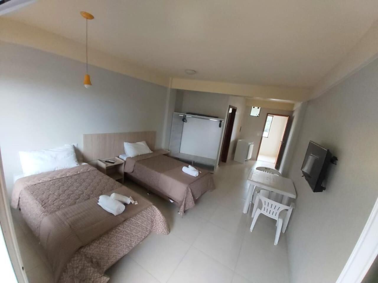 A hotel room with two beds, a desk, a chair, a TV, and a wardrobe.