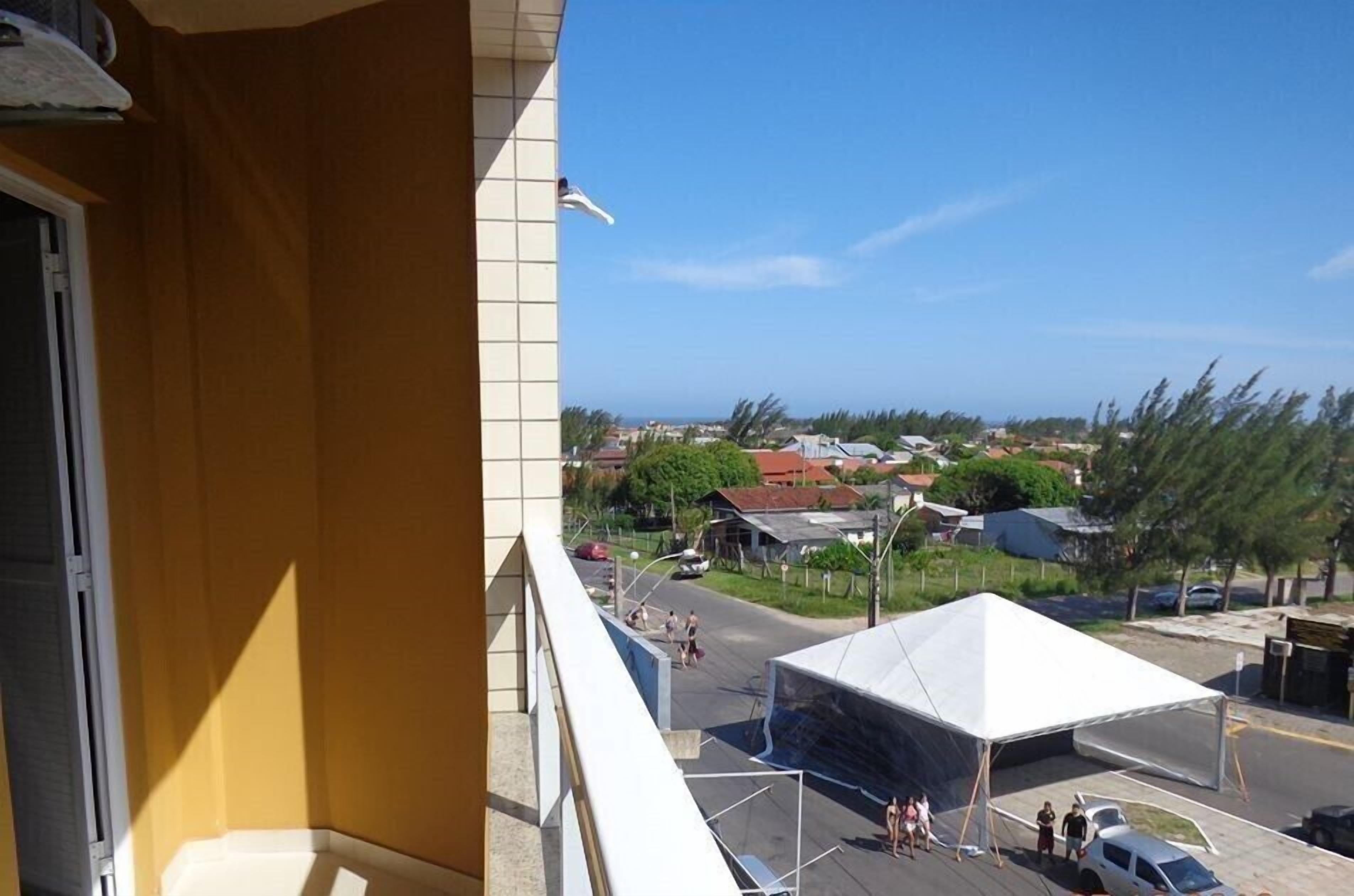 Een balkon met uitzicht op een stad, een witte tent en een paar mensen.
