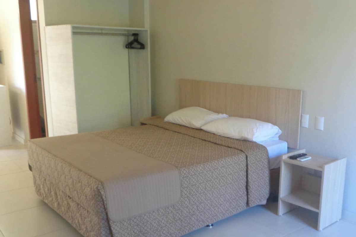 A neatly arranged hotel room with a bed, a bedside table, and a wardrobe.