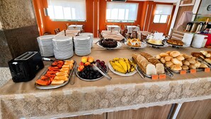A buffet with various food items, plates, and a toaster. - Lebanon Praia Hotel (Tramandai)