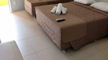 Camera d'albergo con due letti, una finestra con tende, un condizionatore d'aria e un telecomando su un letto.