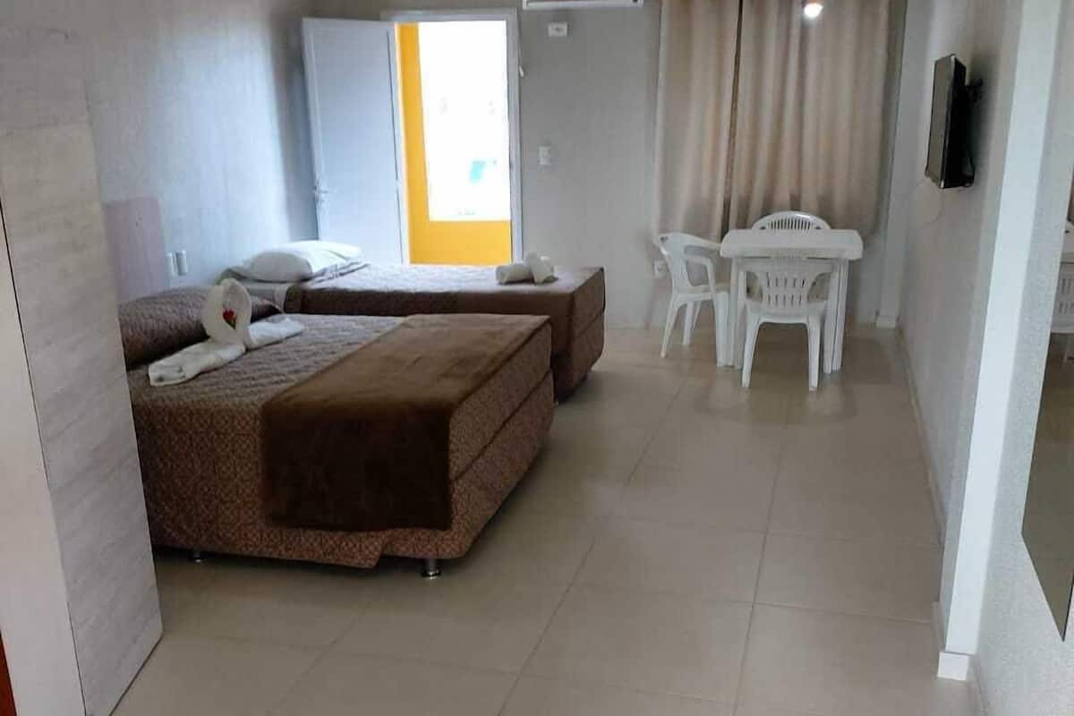 A hotel room with two beds, a small table, and a TV.
