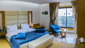 Quarto de hotel com uma cama grande, uma escrivaninha, uma cadeira e uma televisão.