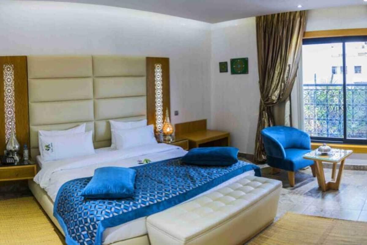 Ein Hotelzimmer mit einem großen Bett, einem Schreibtisch, einem Stuhl und einem Fernseher.