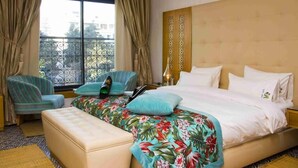 Quarto de hotel com cama, uma cadeira e um banco.