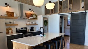 Una cocina moderna con una isla central, taburetes de bar e iluminación colgante.