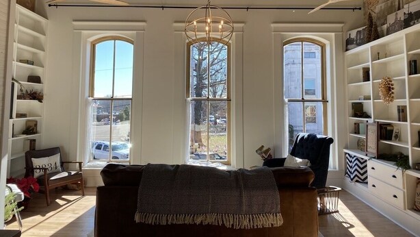 Un salón amplio con un ventanal grande, ventilador de techo y estanterías empotradas.