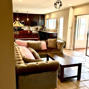 Relax in a spacious living area with a plush sofa and kitchenette, perfect for unwinding.