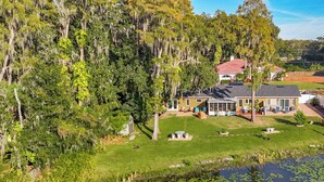 A house surrounded by lush greenery and a pond with lily pads.