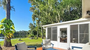 A patio with outdoor furniture, a covered seating area, and a view of a lake and trees.
