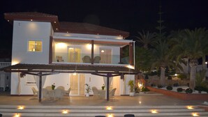 Ein zweistöckiges Haus mit Balkon, Sitzbereich im Freien und einem Pool mit Liegestühlen.