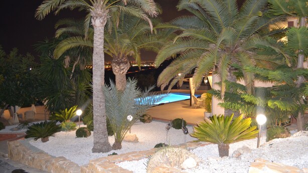 Ein Nachtblick auf ein Resort mit Palmen, einem Schwimmbad und einem gut beleuchteten Patio.