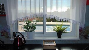 Ein Fenster mit Spitzenvorhängen, einem Blumentopf und einem Wasserkocher auf der Fensterbank.