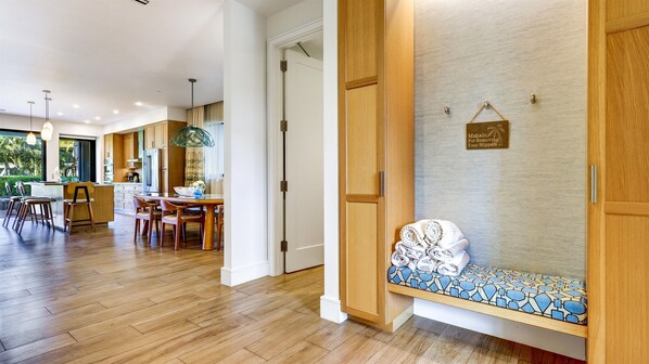A modern kitchen with wooden cabinets, a dining area with a round table and chairs, and a bench with a patterned cushion.