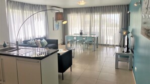 Une cuisine moderne dotée d’un îlot central, d’un coin repas avec des chaises et d’un espace de vie avec un canapé.