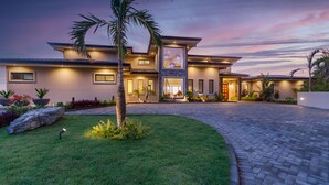 Una moderna casa a due piani con un prato curato e un vialetto lastricato che conduce all'ingresso.