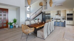 Una cocina amplia con electrodomésticos modernos, un comedor con mesa y sillas de madera, y una escalera que conduce a un nivel superior.