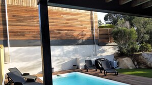 A wooden deck with a swimming pool, lounge chairs, and a covered grill area. - NEAR PINARELLO BEACH - LUXURY VILLA FOR 9 PEOPLE - AIR-CONDITIONED WITH SWIMMING POOL (Sainte-Lucie de Porto-Vecchio)