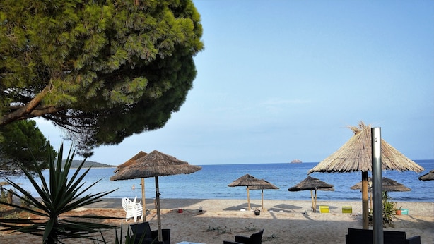 A beach with thatched umbrellas, lounge chairs, and a clear view of the sea. - NEAR PINARELLO BEACH - LUXURY VILLA FOR 9 PEOPLE - AIR-CONDITIONED WITH SWIMMING POOL (Sainte-Lucie de Porto-Vecchio)