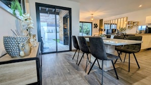 A modern kitchen with a large island, dark chairs, and a glass door leading to a patio. - NEAR PINARELLO BEACH - LUXURY VILLA FOR 9 PEOPLE - AIR-CONDITIONED WITH SWIMMING POOL (Sainte-Lucie de Porto-Vecchio)
