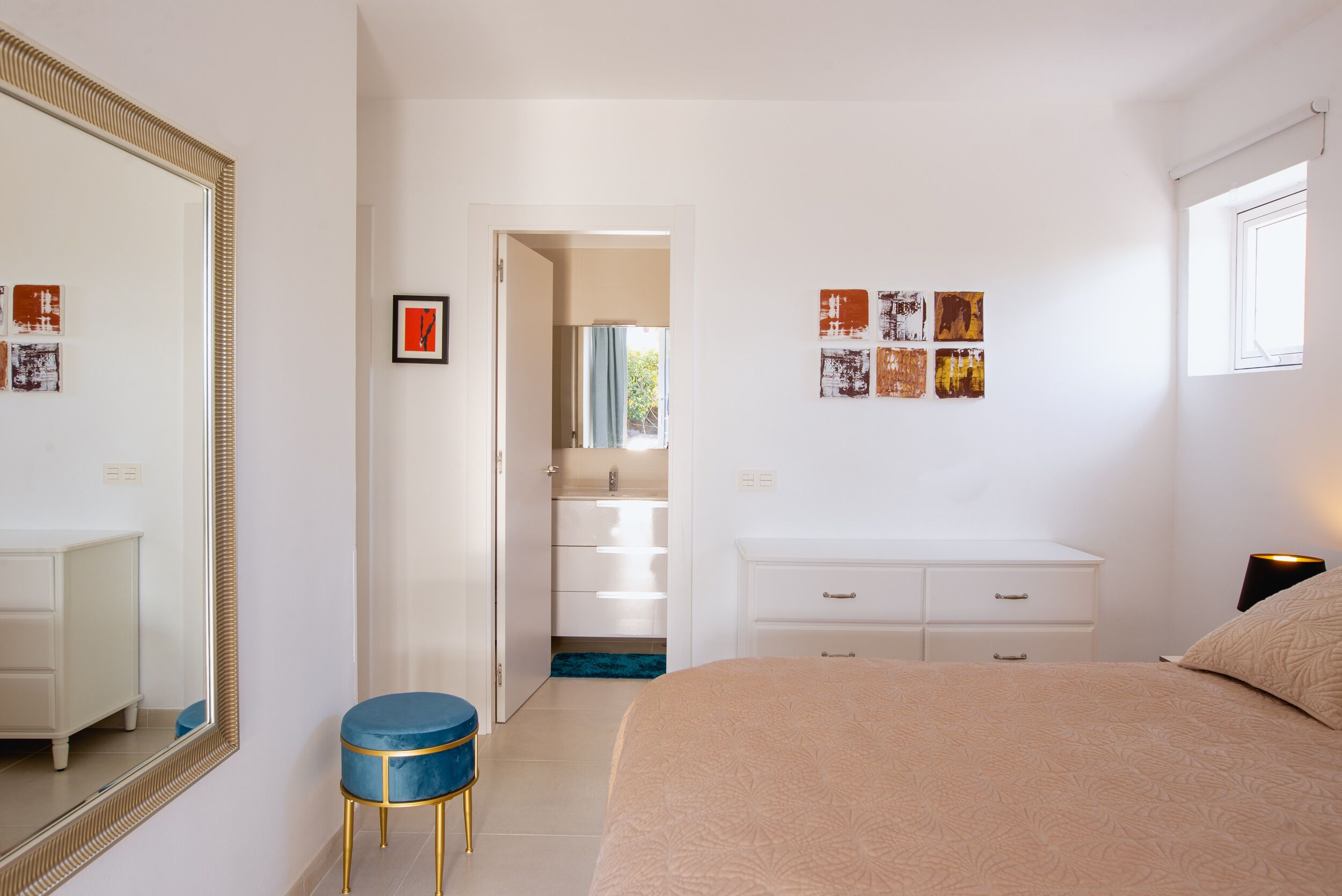 A bedroom with a large mirror, a bed, a vanity, and a walk-in closet.