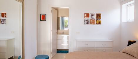 A bedroom with a large mirror, a bed, a vanity, and a walk-in closet.