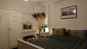 A bedroom with a bed, a dresser, a mirror, a lamp, and a framed picture on the wall. - 4stars FRENCH EMBASSY One Bedroom Apartment, AMZEI historic downtown, very quiet (Bucharest)